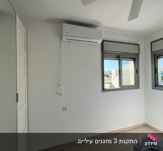 מזגן מותקן על קיר בחדר עם מאוורר תקרה